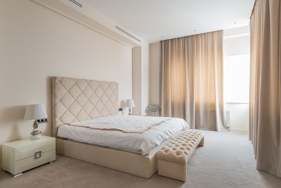 Serene contemporary bedroom with a beige upholstered bed, soft nightstand lamps and warm neutral tones