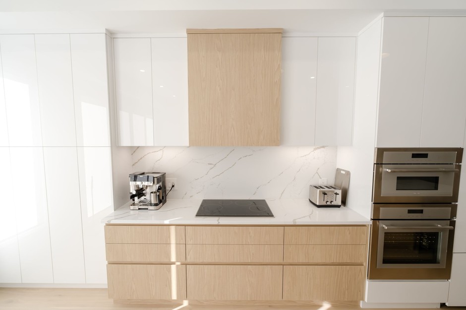 Minimalist modern kitchen with light-oak handleless cabinetry and a marble backsplash