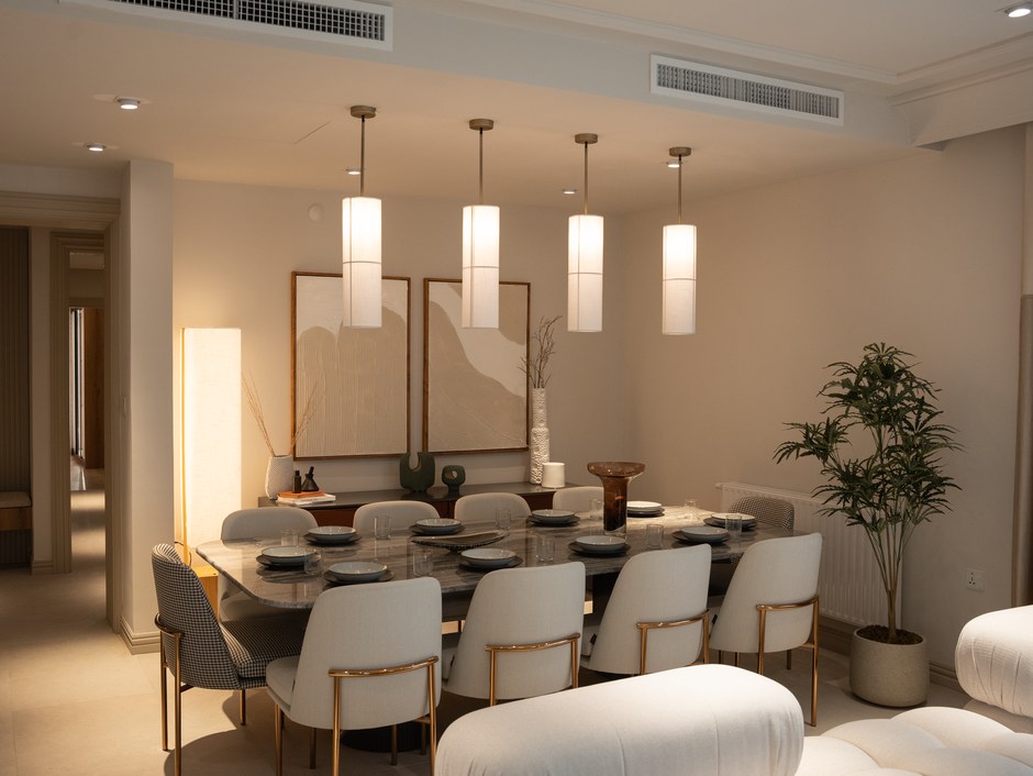 Upscale contemporary dining room with a marble table, gold-legged upholstered chairs and statement drum pendant lights