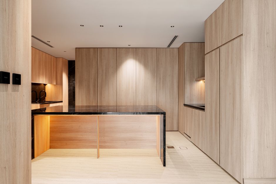 Sleek fitted kitchen with wood-panelled cabinetry and black marble countertops